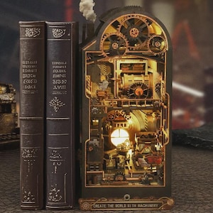 May include: An illuminated steampunk book nook featuring detailed gears, pipes, and machinery. Two vintage books are positioned beside the nook. The base of the nook displays the text "CREATE THE WORLD WITH MACHINERY".