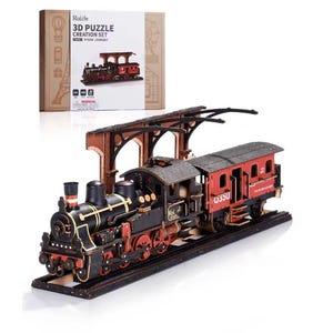 Könnte beinhalten: Ein 3D-Holzpuzzle-Set mit einem Dampflokmodell. Der Zug ist schwarz und rot mit goldenen Akzenten, und das Set enthält einen Bahnhof. Auf der Box steht "3D Puzzle Creation Set Steam Journey".