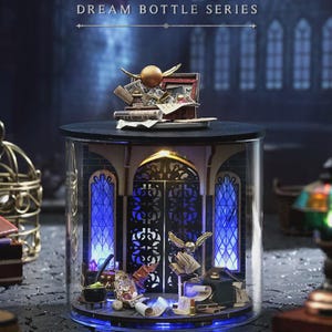 Puede incluir: Un diorama en miniatura detallado dentro de un cilindro de vidrio transparente. Presenta ventanas arqueadas, una puerta central y varios objetos en miniatura, iluminados con luces azules y amarillas. El texto "DREAM BOTTLE SERIES" es visible.