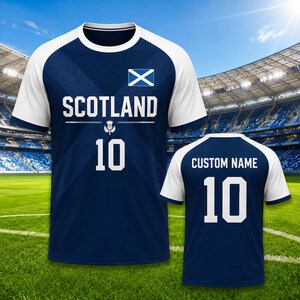 May include: A navy blue and white soccer jersey with the word "SCOTLAND" and the number "10" printed on the front. The Scottish flag is displayed on the upper chest. The back of the jersey has "CUSTOM NAME" and the number "10".