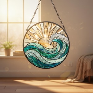 Könnte beinhalten: Rundes Buntglasfenster mit einer Sonne und einer Ozeanwelle. Die Sonne ist golden, und die Welle ist türkis und grün mit klaren Verzierungen. Das Kunstwerk wird von einer Kette gehalten.