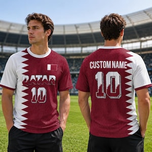 K&ouml;nnte beinhalten: Bordeaux-wei&szlig;es Fu&szlig;balltrikot mit dem Wort "QATAR" und der Nummer "10" auf der Vorderseite. Das Trikot hat ein wei&szlig;es Zickzack-Design an den Seiten und &Auml;rmeln. Auf der R&uuml;ckseite des Trikots steht der Text "CUSTOM NAME" und die Nummer "10".