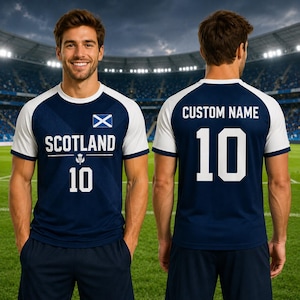 May include: Navy blue and white soccer jersey with the word "SCOTLAND" and the number "10" printed on the front. The jersey features the Scottish flag and a thistle emblem. The back of the jersey has the number "10" and space for a custom name.