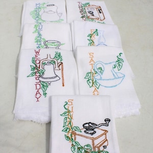 May include: Set of seven white tea towels with embroidered days of the week and a different kitchen item for each day. The items include a teapot, a pitcher, a bell, a pitcher, a lamp, a cabinet, and a coffee grinder.