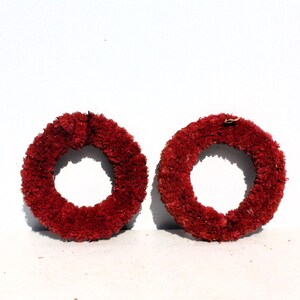 May include: Two red wreaths made of dried flowers. The wreaths are circular and have a diameter of about 10 inches.