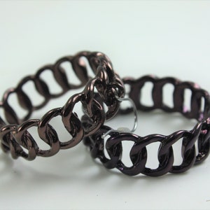 May include: Two dark brown chain link hoop earrings. The earrings are made of metal and have a shiny finish.