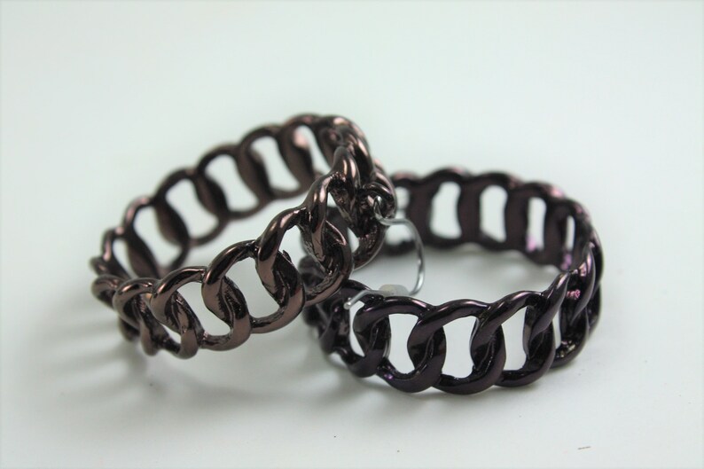 May include: Two dark brown chain link hoop earrings. The earrings are made of metal and have a shiny finish.