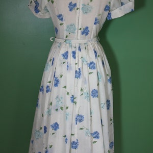 May include: A white dress with a blue floral print and a back zipper closure. The dress has short sleeves and a full skirt.