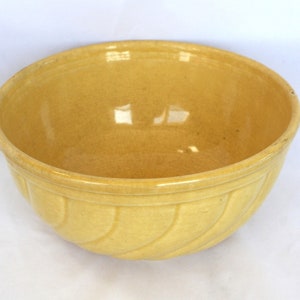 May include: A yellow ceramic mixing bowl with a fluted design. The bowl is empty and has a glossy finish.