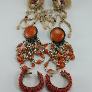 May include: A pair of long, orange and gold beaded earrings with a large orange stone and a pair of hoop earrings made of small orange beads.