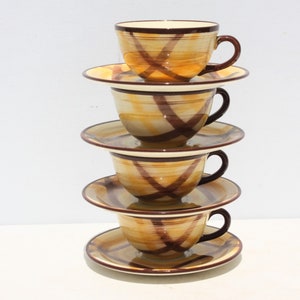 May include: A stack of four ceramic teacups and saucers with a brown and yellow striped pattern.