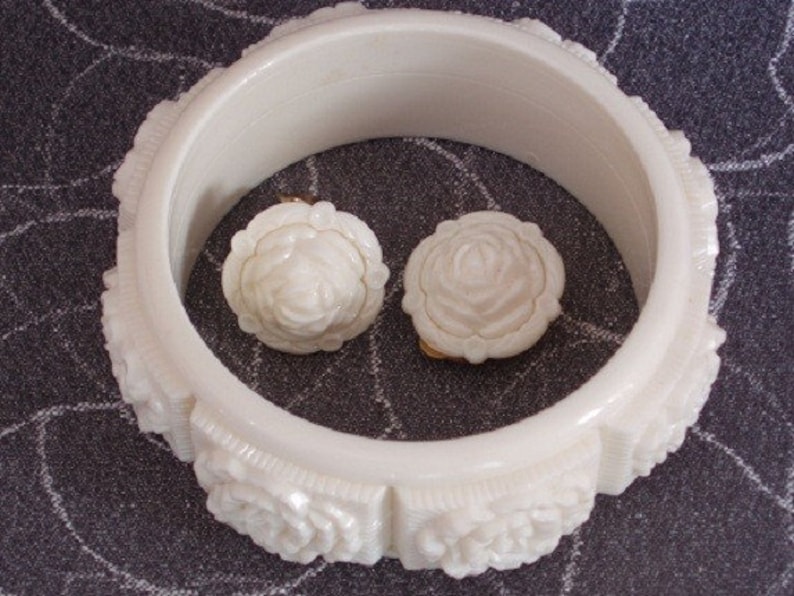Pu&ograve; includere: Braccialetto bianco in plastica con un design a rosa scolpita. Il braccialetto &egrave; decorato con due orecchini in plastica bianca a forma di rosa.
