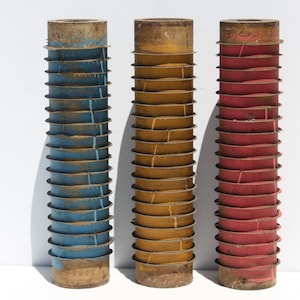 May include: Three wooden rollers with different colored paint. The roller on the left is blue, the middle roller is yellow, and the roller on the right is red.