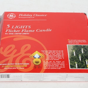 May include: A red box with a white GE logo and the text "Holiday Classics" on the front. The box contains a set of 5 GE Flicker Flame Candles with a total lighted length of 8 ft. The box also features a 3-year limited warranty and a UL safety listing.