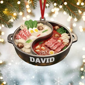 Könnte beinhalten: Runder, schwarzer Ornament in Form eines Yin-Yang-Hotpots, gefüllt mit verschiedenen Lebensmitteln. Das Ornament hat ein rotes Band zum Aufhängen und den Namen "DAVID" in weißem Text. Der Hotpot enthält Fleisch, Gemüse und Nudeln.