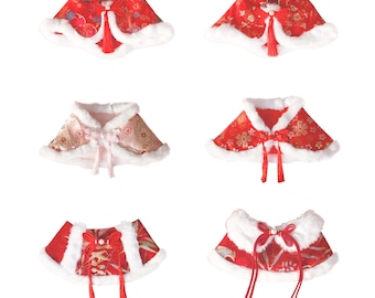 May include: A collection of six decorative capes. The capes feature a red or pink floral pattern with white faux fur trim. Each cape has a decorative bow and tassel. The capes are designed with a traditional Asian aesthetic.