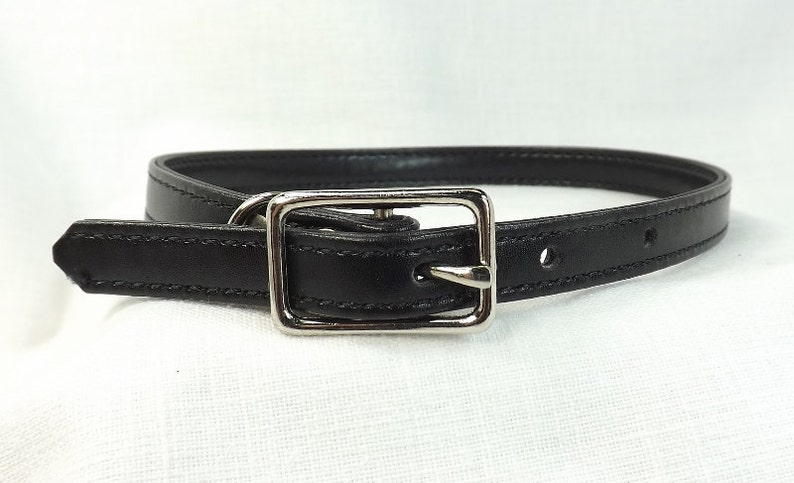 May include: A black leather belt with a silver buckle. The belt is about 1 inch wide and has a simple design.