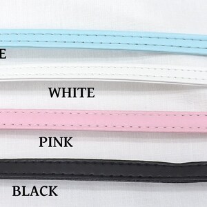 May include: Four leather straps in different colors: blue, white, pink, and black. The straps are lined up horizontally on a white surface. The colors are labeled below each strap.