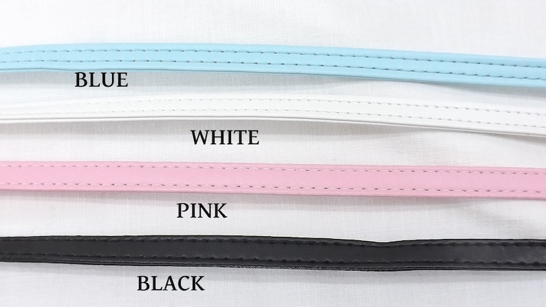 May include: Four leather straps in different colors: blue, white, pink, and black. The straps are lined up horizontally on a white surface. The colors are labeled below each strap.