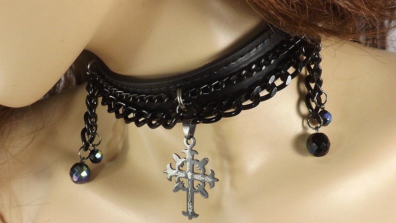 May include: Black leather choker necklace with a silver cross pendant and black crystal beads.