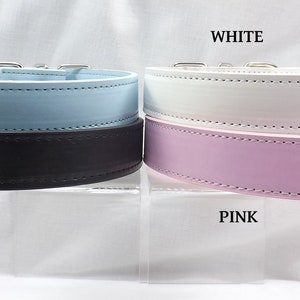 May include: Four leather dog collars in different colors: blue, black, white, and pink. The collars are displayed on a white surface.