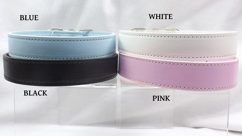 May include: Four leather dog collars in different colors: blue, black, white, and pink. The collars are displayed on a white surface.