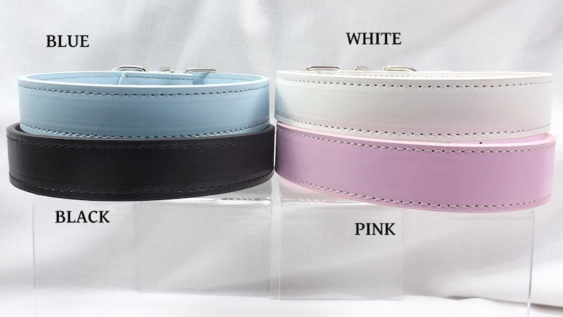 May include: Four leather dog collars in different colors: blue, black, white, and pink. The collars are displayed on a white surface.
