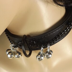May include: Black leather choker with a silver chain and multiple silver bells hanging from it.