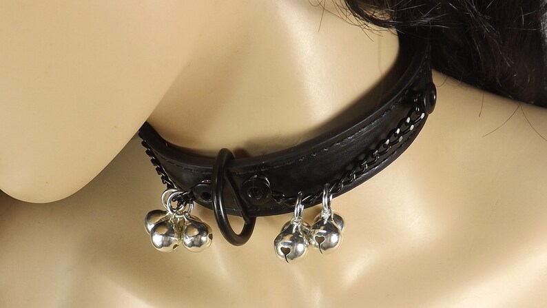 May include: Black leather choker with a silver chain and multiple silver bells hanging from it.