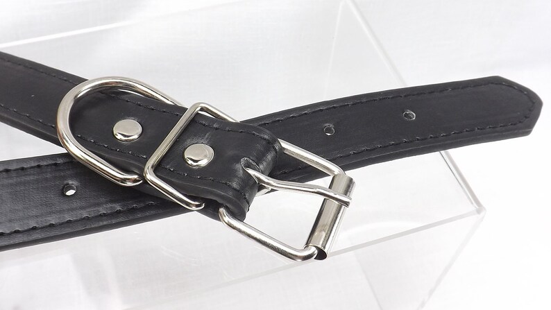 May include: Black leather dog collar with a silver buckle and a silver D-ring. The collar has multiple holes for adjusting the size.