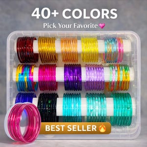Puede incluir: Un recipiente de plástico transparente lleno de pulseras de cristal de colores. La imagen muestra una variedad de colores, incluyendo rojo, amarillo, naranja, verde, azul y morado. El texto en la parte superior dice "40+ COLORS" y "Pick Your Favorite". El texto inferior dice "BEST SELLER".