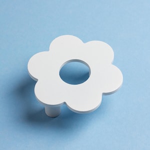 Può includere: Pomello per armadio bianco a forma di fiore, con un foro centrale e un gambo cilindrico corto. Il pomello è posto su uno sfondo azzurro chiaro, offrendo un'estetica pulita e minimalista. Questo hardware decorativo è adatto per cassetti e armadi.