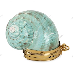 Könnte beinhalten: Eine dekorative Schmuckschatulle in Form einer Muschelschale. Die Schale ist türkis mit brauner Marmorierung. Der Sockel ist aus goldfarbenem Metall mit einem Scharnier und einer kleinen Schlaufe für einen Verschluss. Ein einzigartiges Schmuckstück.