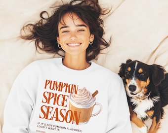 May include: White sweatshirt with the text "PUMPKIN SPICE SEASON" and a watercolour illustration of a pumpkin spice latte. The text "IF IT'S NOT PUMPKIN FLAVORED, I DON'T WANT IT." is also printed on the sweatshirt. A dog is next to the person wearing the sweatshirt.