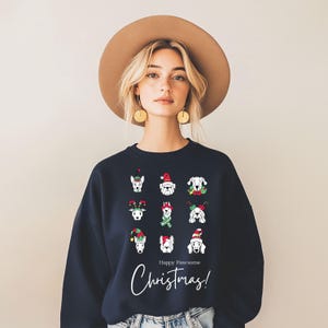 Op de afbeelding: Marineblauw sweatshirt met een kerstthema hondenontwerp. Het sweatshirt toont illustraties van honden met feestelijke hoeden en accessoires. De woorden "Happy Pawsome Christmas!" zijn in een cursief lettertype geschreven.
