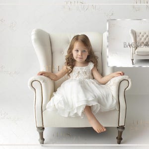 May include: A young girl in a white dress sits in a cream-colored wingback chair. The chair has a high back, rolled arms, and wooden legs. The background is a white wall with subtle text. A smaller image of the chair is in the upper right corner.