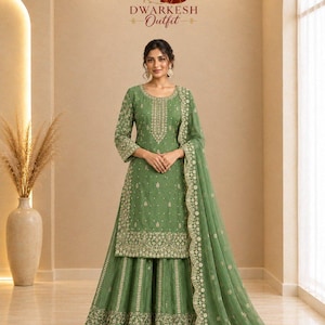 May include: A sage green three-piece ensemble featuring a long-sleeved tunic, a flared skirt, and a matching dupatta. The garments are adorned with intricate gold embroidery, floral patterns, and beadwork. The text DWARKESH Outfit is visible.