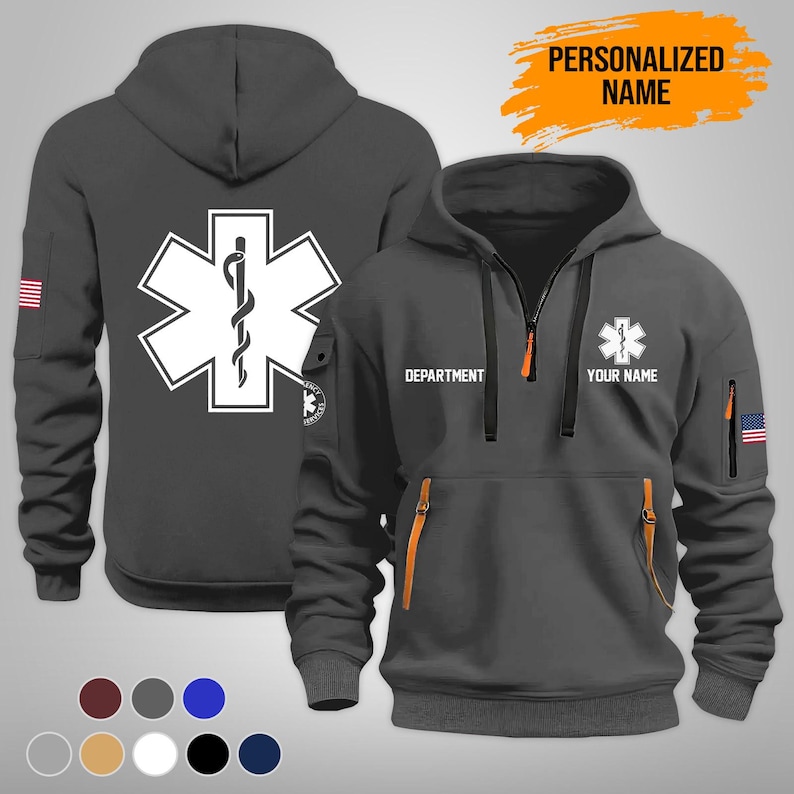 Puede incluir: Una sudadera con capucha gris oscuro con un emblema blanco de la Estrella de la Vida y una cremallera. La sudadera tiene capucha, bolsillos y el texto "DEPARTMENT" y "YOUR NAME". La bandera americana est&aacute; en la manga. Las palabras "PERSONALIZED NAME" est&aacute;n en una pancarta naranja.