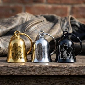 May include: Three bell-shaped keychains in gold, silver, and black finishes, each featuring a circular ring at the top. Each bell is engraved with a distinct line-art illustration of two people, showcasing detailed outlines of figures in various poses.