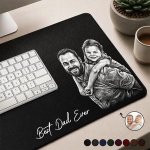 Może przedstawiać: Czarna prostokątna podkładka pod biurko z szczegółowym szkicem ojca niosącego dziecko na plecach. Napis "Best Dad Ever" jest napisany białym skryptem. Biała klawiatura jest widoczna po lewej stronie.
