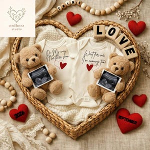 Könnte beinhalten: Ein herzförmiger Weidenkorb enthält zwei Baby-Bodys mit Text und roten Herzen, flankiert von Teddybären, die Ultraschallfotos halten. Holzblöcke buchstabieren "LOVE", und rote Herzdekorationen sind verstreut. Das Thema ist eine Schwangerschaftsankündigung.