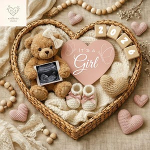 Könnte beinhalten: Ein herzförmiger Weidenkorb enthält einen Teddybären, einen Ultraschallscan und Babyschuhe. Ein rosa herzförmiges Schild liest "It's a Girl". Holzblöcke buchstabieren "2026". Häkelherzen und Holzperlen vervollständigen die Anordnung.