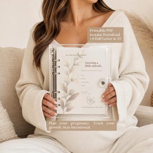 Könnte beinhalten: Ein transparenter Ordner mit einem Schwangerschaftsplaner mit floralen Illustrationen und dem Text "Growing a little miracle." Der Planer enthält Abschnitte zur Verfolgung von Informationen und den Text "Plan your pregnancy. Track your growth. Stay intentional."