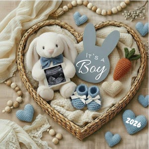 Könnte beinhalten: Ein herzförmiger Weidenkorb enthält ein weißes Plüschkaninchen mit blauer Fliege, ein Ultraschallbild und blaue Babyschuhe. Ein graues, hasenförmiges Schild liest sich "It's a Boy". Zusätzlich eine gehäkelte Karotte, Herzen und Holzperlen.