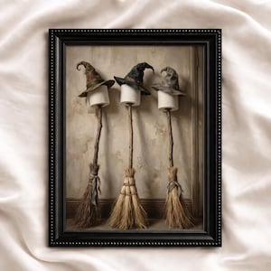 May include: A framed wall art print featuring three broomsticks standing upright, each topped with a roll of white toilet paper and a pointed witch hat in brown, black, and gray. The broomsticks have wooden handles and straw bristles.