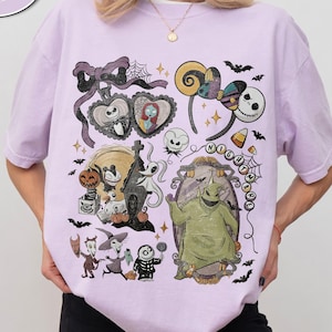 Puede incluir: Una camiseta color orqu&iacute;dea con un estampado gr&aacute;fico de personajes y s&iacute;mbolos de Pesadilla antes de Navidad, incluyendo a Jack Skellington, Sally, Oogie Boogie, Zero y orejas de rat&oacute;n, con el texto Comfort Colors Orchid.