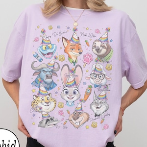 May include: A light purple t-shirt featuring cartoon characters from Zootopia, each wearing a party hat. The shirt has the word "Orchid" in a white circle at the bottom left. The characters include Judy Hopps, Nick Wilde, and Flash.