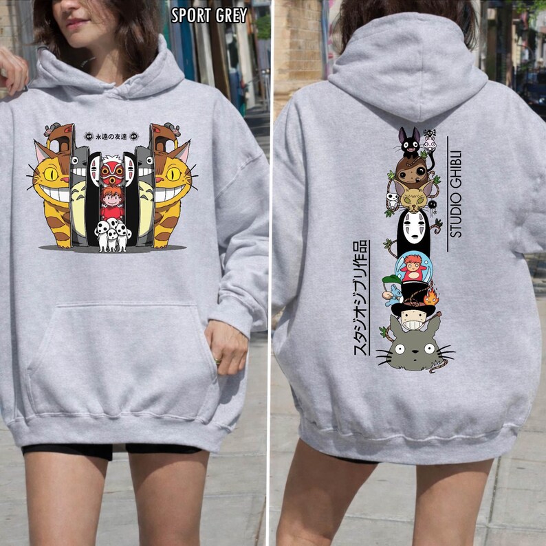 May include: Sport grey hoodie featuring colorful cartoon characters on the front and back. The front design includes smiling cat-like creatures and other characters. The back displays a vertical stack of animated figures with "STUDIO GHIBLI" text.