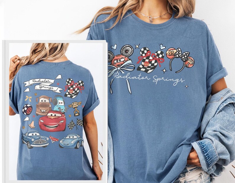 May include: A light blue t-shirt featuring a graphic of the Cars movie characters and the text "Radiator Springs". The design includes images of race cars, checkered flags, and Mickey Mouse ears.