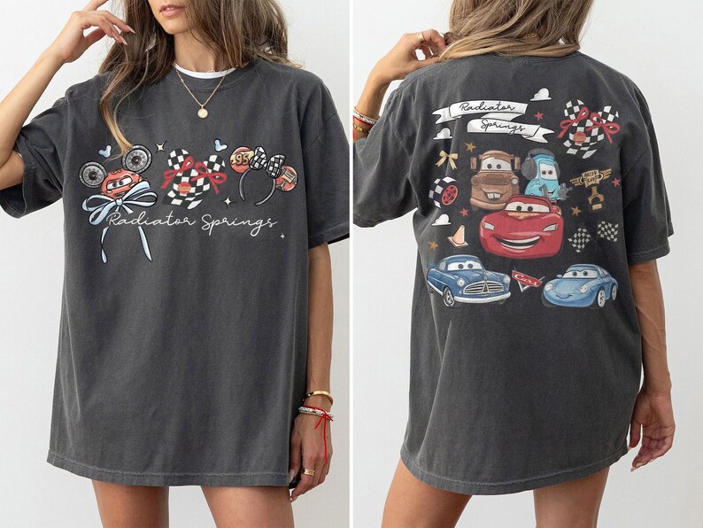 May include: Dark gray t-shirt featuring a front graphic of a race car, Mickey Mouse ears, and the text "Radiator Springs." The back of the shirt displays various cartoon cars and the words "Radiator Springs."
